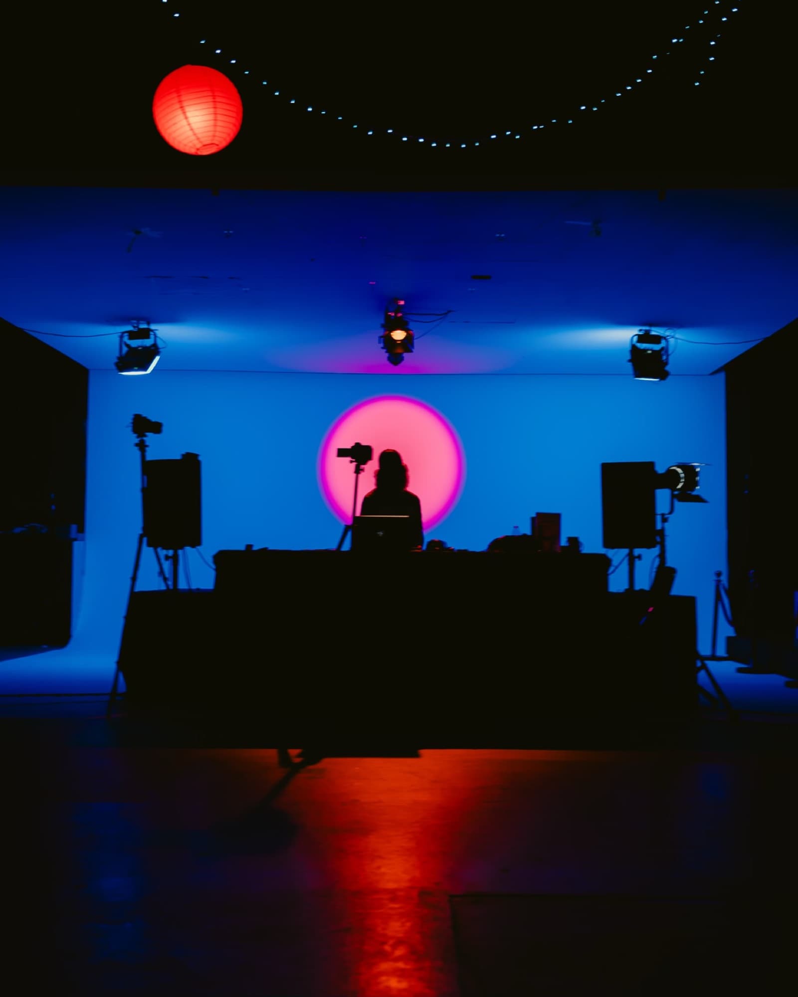 The DJ booth glowing blue under a red balloon light