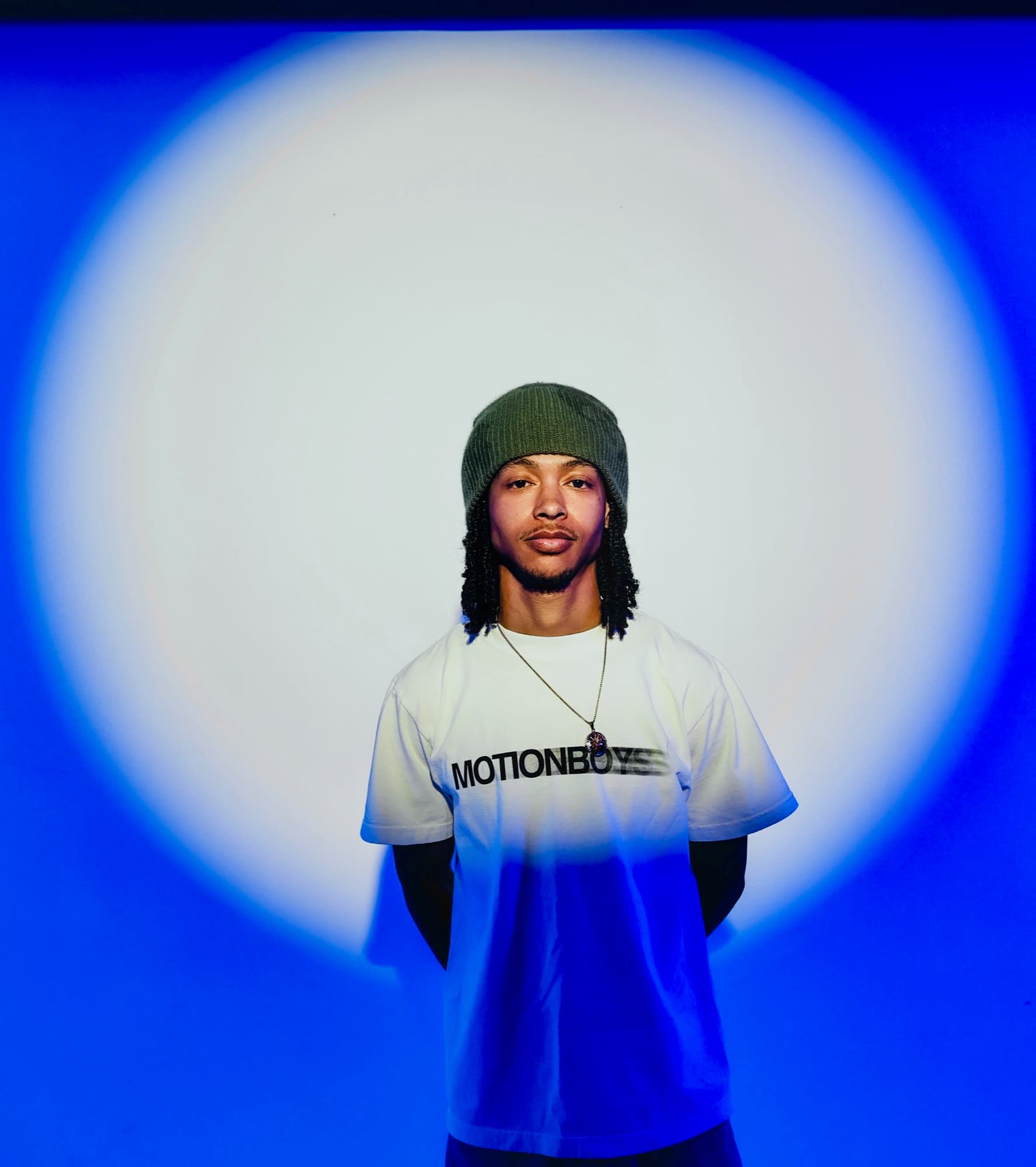 A portrait in a white spotlight on a blue backdrop